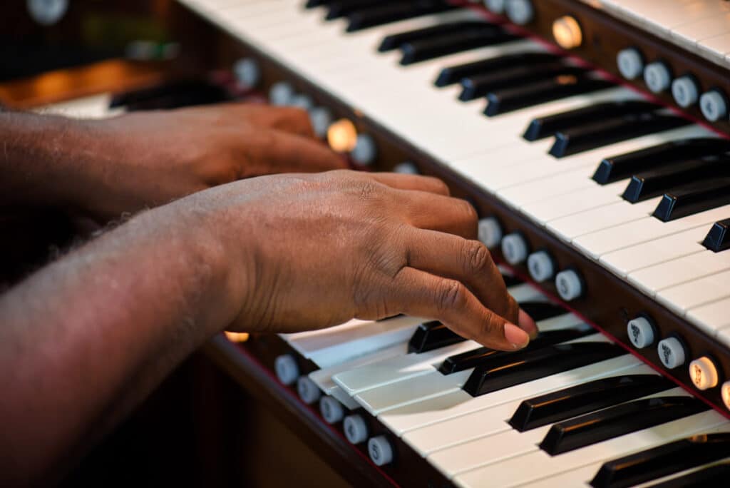 Hands playing keyboard supported by Catholic music resources, ministry resources, and liturgical music