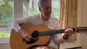 Photo of Steve Petrunak playing guitar from the video discussing changing the style of a song for liturgy