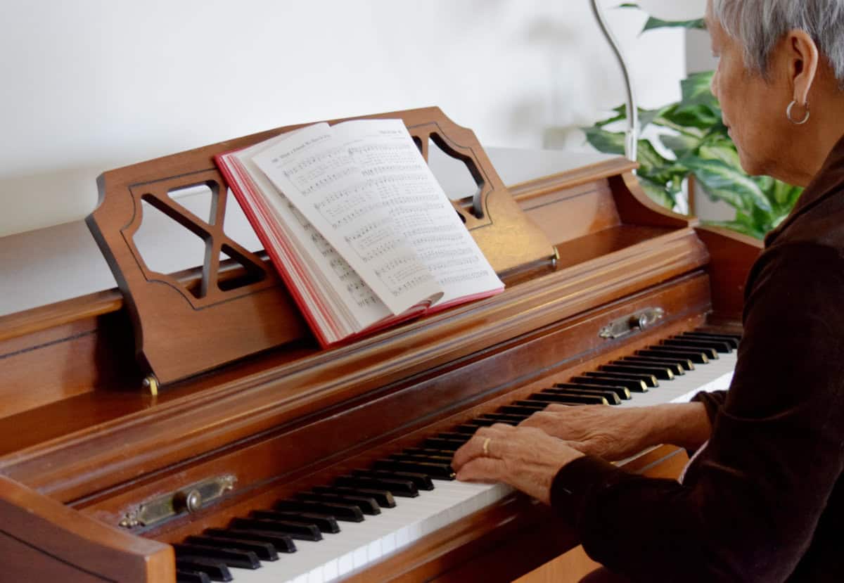 A woman plays piano from a hymnal to illustrate the blog article on using common hymn tunes to expand repertoire.