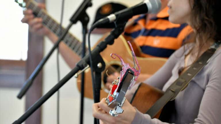 woman holding a guitar in front of a microphone to illustrate finding balance in music ministry