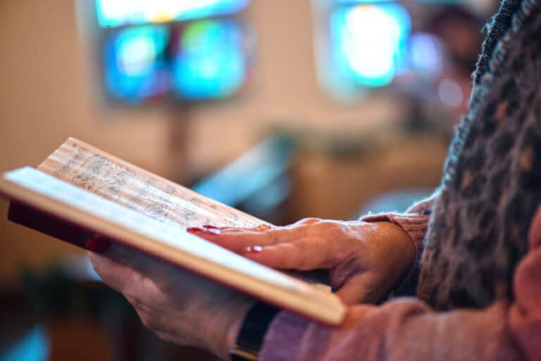 Photo of a woman holding a hymnal to accompany the article on cultural appropriation in music