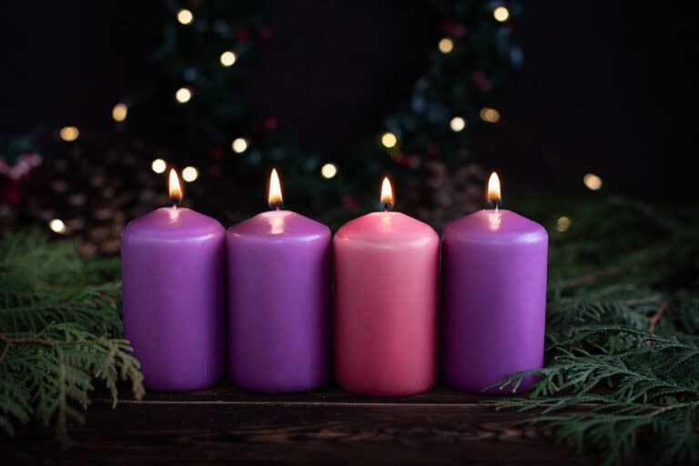 A row of four burning candles to accompany the article on songs for Advent