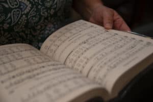 Photo of a woman with a hymnal to represent the topic of seasonal music planning for liturgy