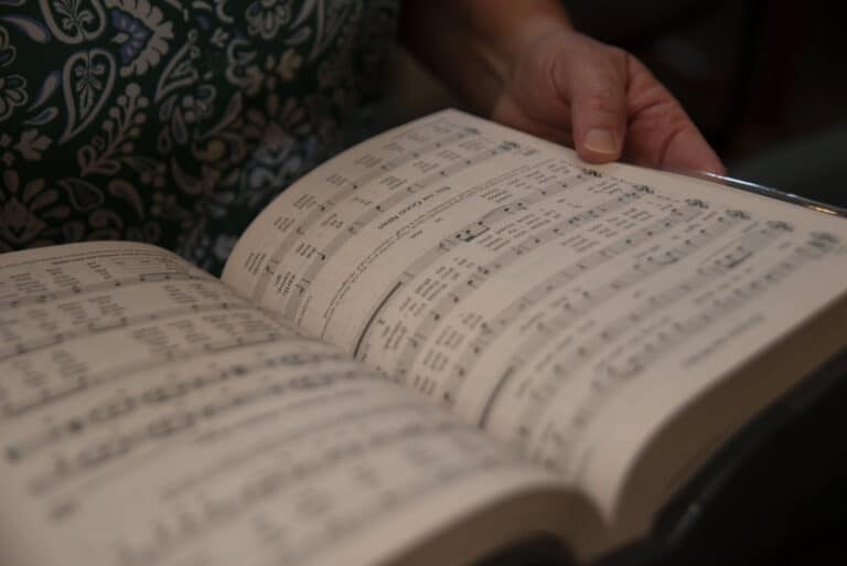 Photo of a woman with a hymnal to represent the topic of seasonal music planning for liturgy